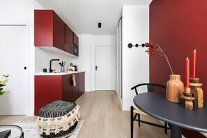Eine moderne Küche mit roten Schränken, einer weißen Arbeitsplatte und einem Essbereich mit Tisch und Stühlen.