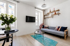 Ein modernes Wohnzimmer mit einer Couch, einem Couchtisch, einem an der Wand befestigten Fernseher und einem Bücherregal.