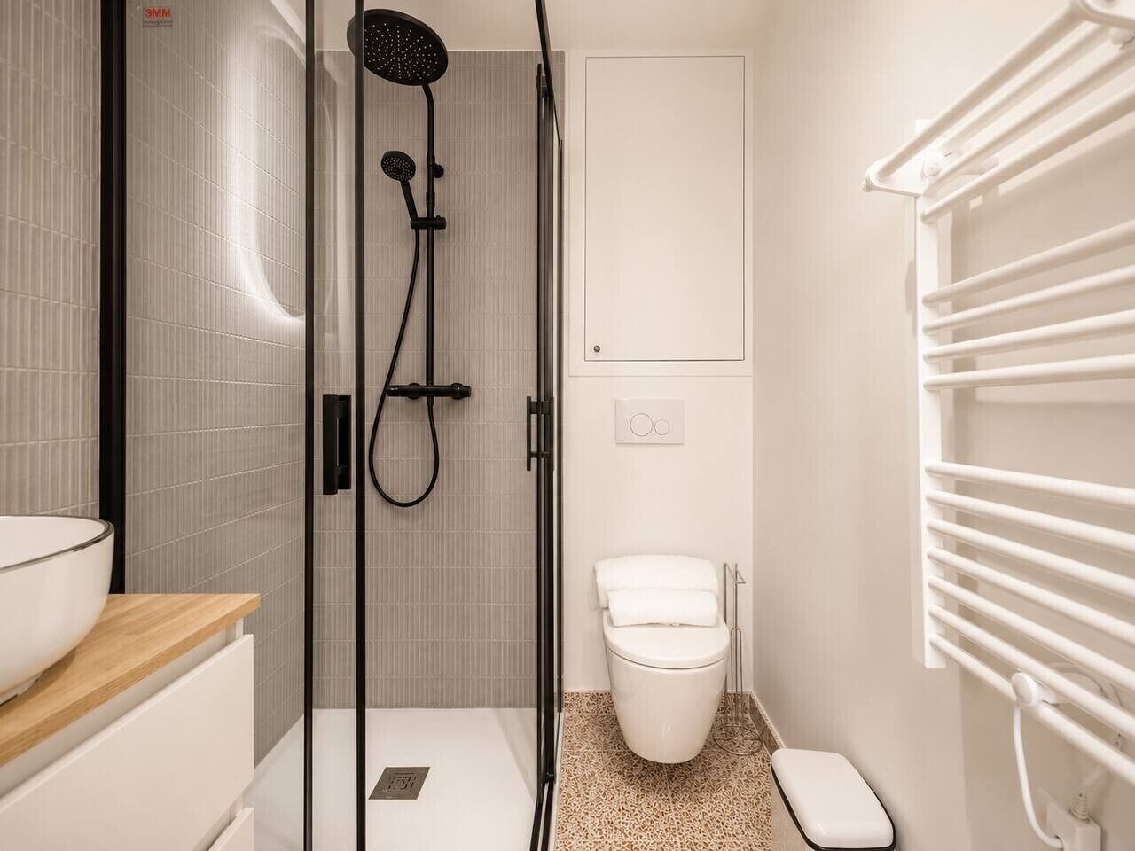 A modern bathroom with a glass shower enclosure, a white toilet, and a towel rack.