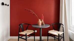 A room with two black chairs, a round table, and a red wall. - Lavie Maison : Charming Studio near to Montmartre (Paris)