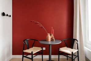 A room with two black chairs, a round table, and a red wall. - Lavie Maison : Charming Studio near to Montmartre (Paris)