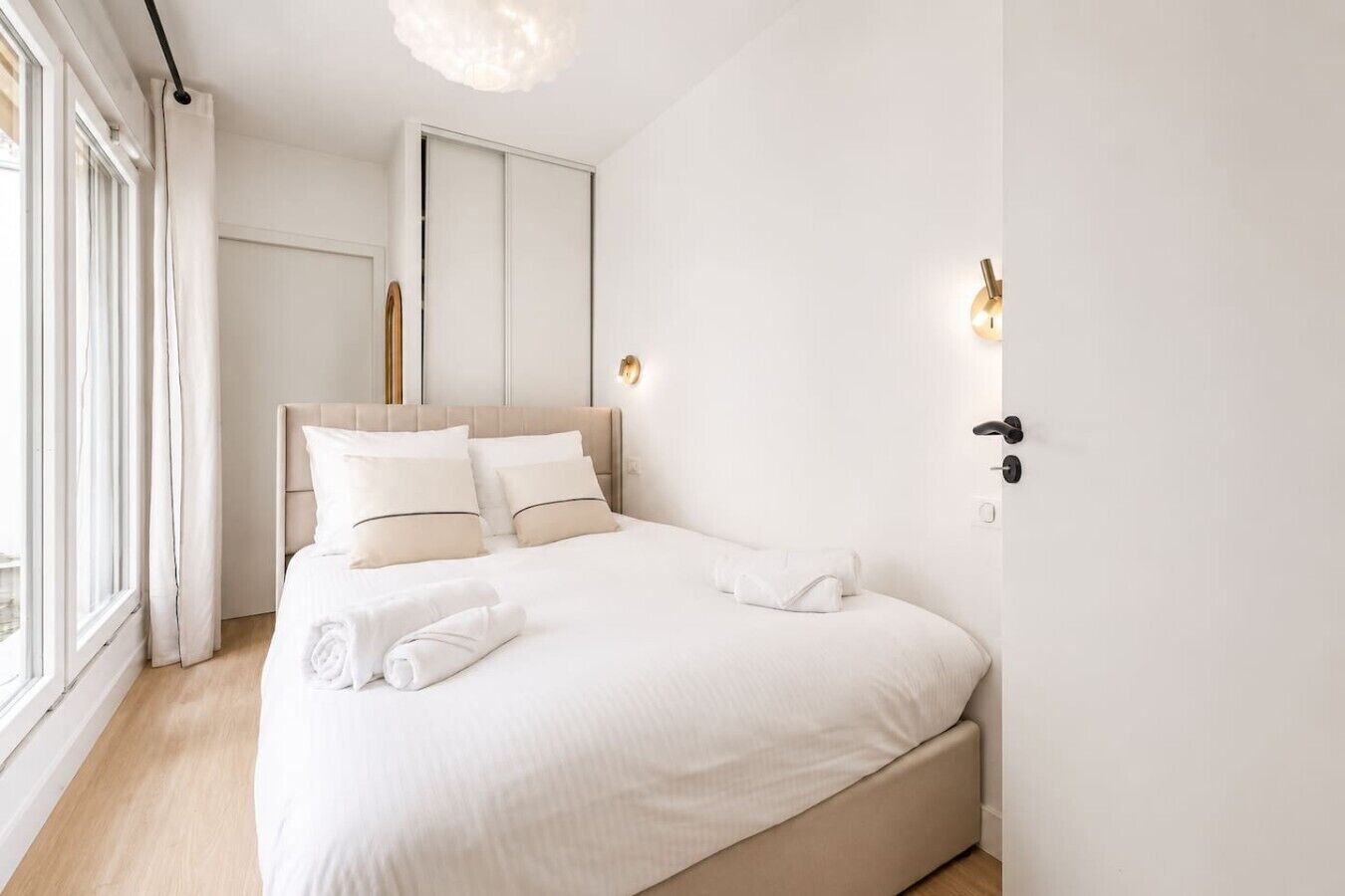 A modern bedroom with a large bed, a wardrobe, and a window with curtains.