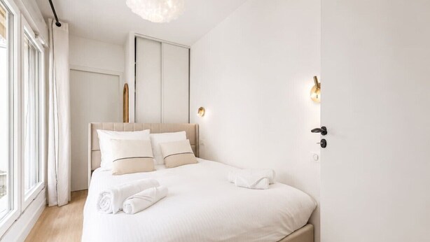 A modern bedroom with a large bed, a wardrobe, and a window with curtains. - Lavie Maison : Cozy Apartment near Montmartre (Paris)