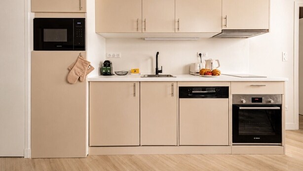 Una cucina moderna con forno a microonde, lavastoviglie, forno e macchina del caffè sul piano di lavoro.
