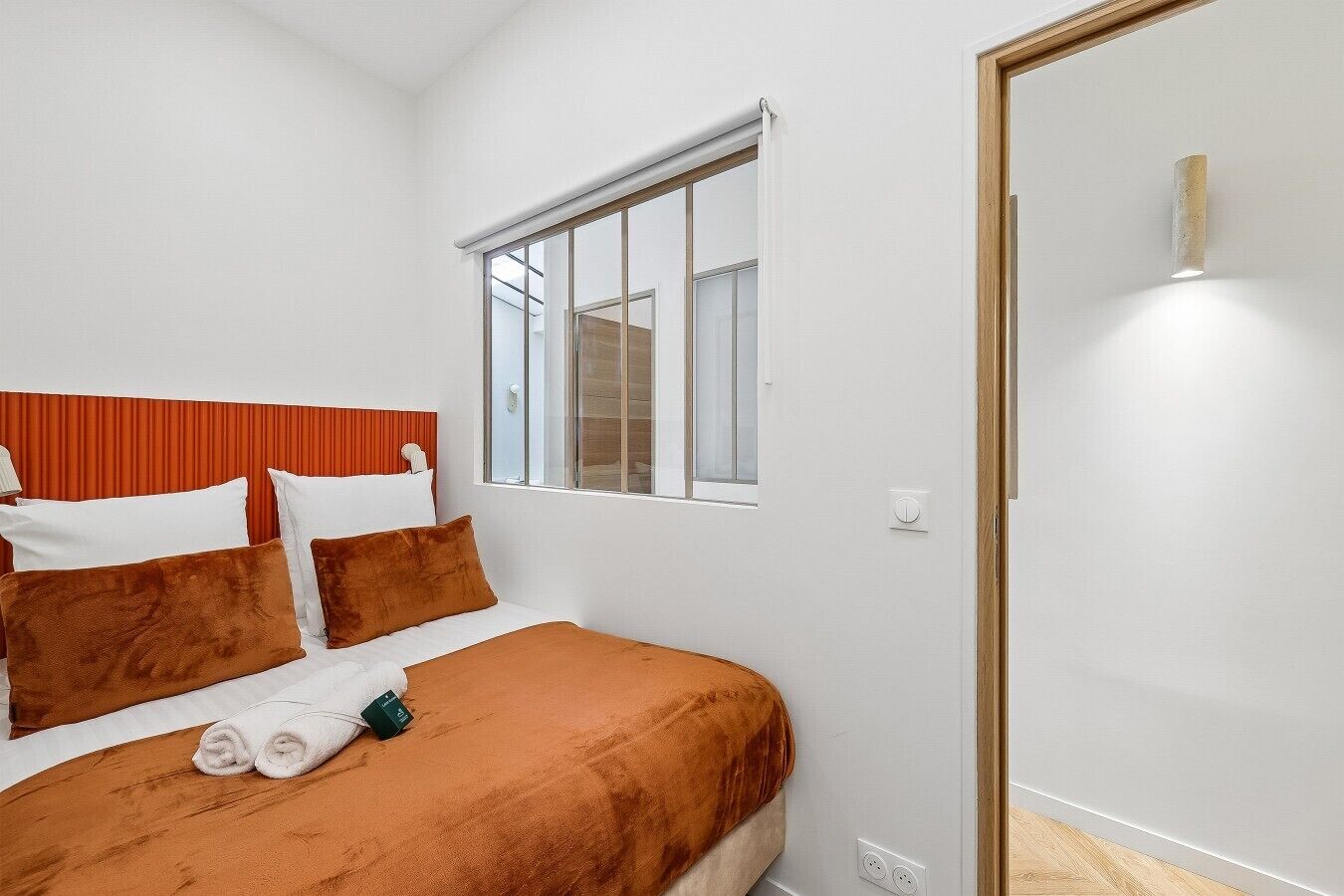 Quarto de hotel com cama, janela e porta.