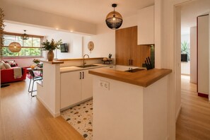 Eine moderne Küche mit Holzarbeitsplatte, weißen Schränken und einer eingebauten Spüle.