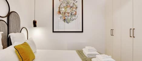 Een hotelkamer met een bed, een lijst met een tijger afbeelding, een nachtkastje met handdoeken, en een kledingkast.