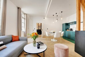 A modern living room with a sofa, coffee table, and a dining area with chairs and a table. - Lavie Maison: Private Cinema in Le Marais (Paris)