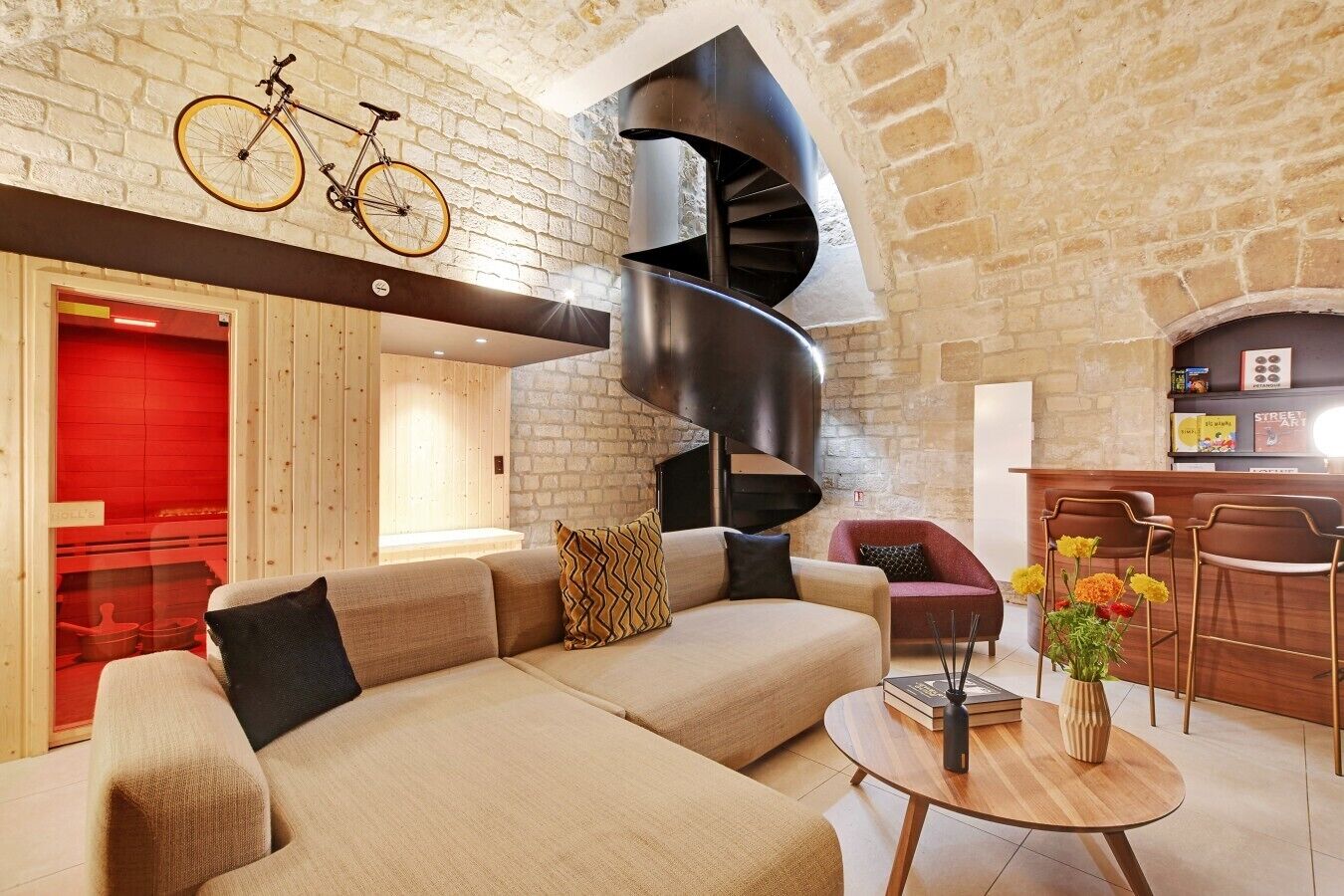 A modern interior with a curved staircase, a sofa set, a round wooden table, and a bar area.