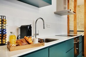 A modern kitchen with a stainless steel sink, a coffee machine, and a breakfast bar with pastries. - Lavie Maison: Private Cinema in Le Marais (Paris)