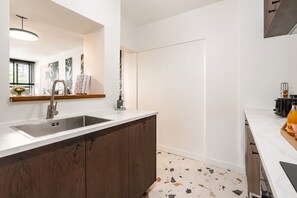 A modern kitchen with a built-in sink, wooden cabinets, and a terrazzo floor. - Lavie Maison | Eiffel Tower & Beaugrenelle (Paris)