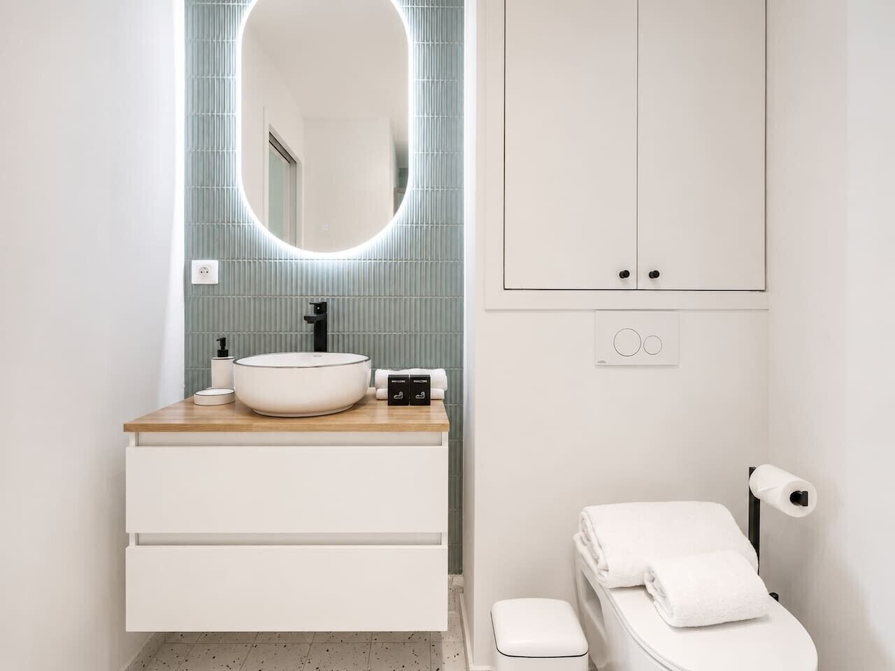 A modern bathroom with a white sink, mirror, and toilet.