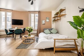A modern bedroom with a bed, bedside table, and a television. - Lavie Maison : Cozy Apartment in the city (Paris)