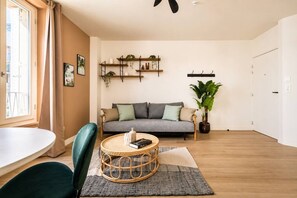 A living room with a sofa, a round coffee table, and a potted plant. - Lavie Maison : Cozy Apartment in the city (Paris)