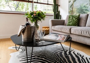 Ein modernes Wohnzimmer mit einem schwarzen Couchtisch, einer Vase mit Blumen, einer Flasche und einer Zeitschrift.