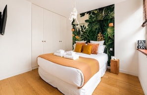 Ein Schlafzimmer mit Bett, weißem Kleiderschrank und Wandgemälde.