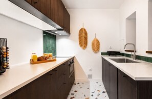 Une cuisine moderne avec des meubles en bois foncé, un plan de travail blanc et un pare-feu.