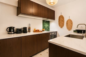 Eine moderne Küche mit Holzschränken, einer weißen Arbeitsplatte, einem Einbauofen und einem Spülbecken.
