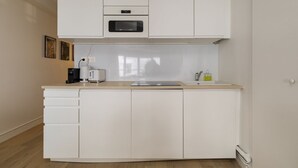 Una cocina compacta con microondas, tostadora y lavabo.