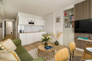 Ein stilvoller Wohnraum mit Küche, Essbereich und Flachbildfernseher.