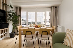 A dining area with a table set for four, a potted plant, and a television on a stand. - Lavie Maison Cozy Flat in Parisian Passage (Paris)
