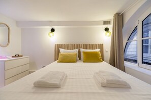 A hotel room with a bed, two bedside lamps, a window with curtains, a dresser, and a mirror. - Lavie Maison Cozy Flat in Parisian Passage (Paris)