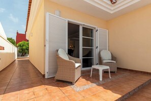 A covered patio with two wicker chairs and a small table, a sliding glass door, and a tiled floor. - Tiffany 16 - Three Bedroom Villa, Sleeps 6 (Callao Salvaje)