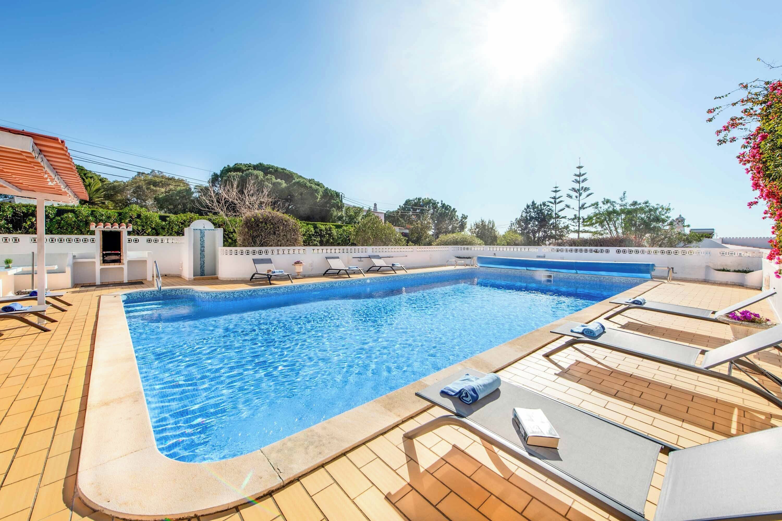 A rectangular swimming pool with clear blue water, surrounded by a tiled deck.