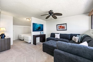 Ein modernes Wohnzimmer mit Sofa, Schreibtisch, Deckenventilator und Bett.