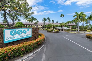 Schild für Country Club Villas mit Parkplatz und Palmen im Hintergrund.