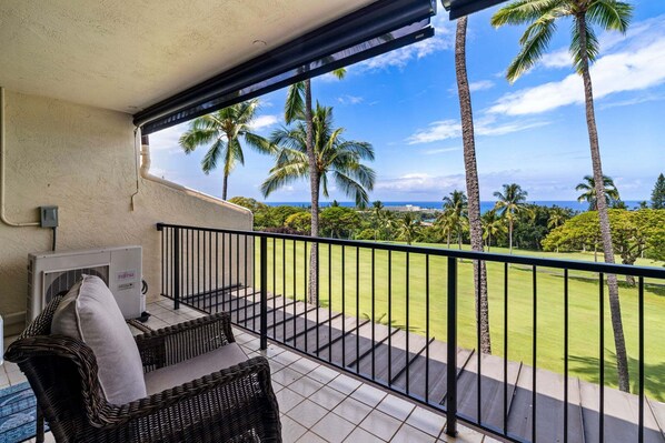 Een balkon met uitzicht op palmbomen en de oceaan.