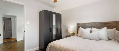 A bedroom with a bed, a nightstand, a lamp, a wardrobe, and a ceiling fan.