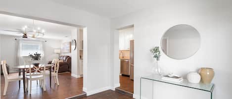 A modern interior with a dining area, kitchen, and a hallway leading to another room.