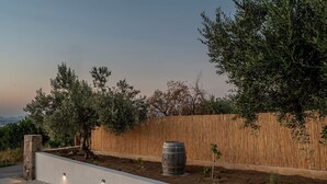 Ein angelegter Garten mit Holzlattenzaun, einem Baum und einem Fass.