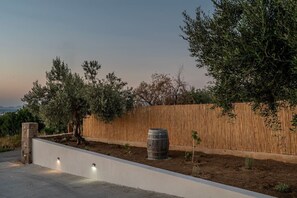 Ein angelegter Garten mit Holzlattenzaun, einem Baum und einem Fass.