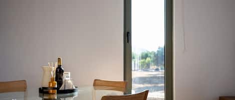 Une table à manger avec des chaises, un plateau en verre et une bouteille de vin.
