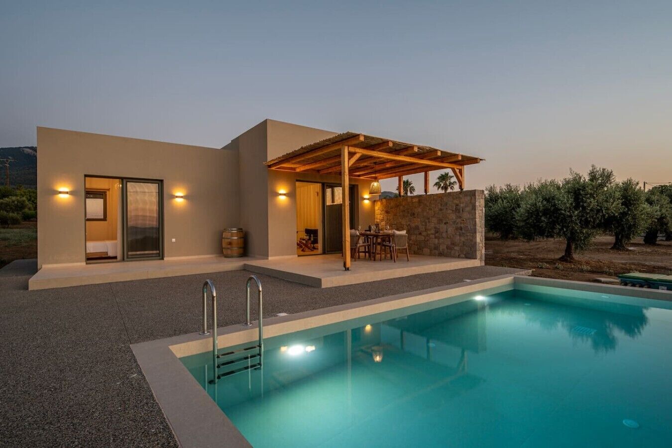 A modern house with a swimming pool, a covered outdoor seating area, and a stone wall.