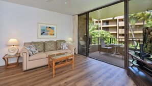 Ein Zimmer mit einer Couch, einem Couchtisch, einem Deckenventilator und Blick auf ein Gebäude mit Balkonen.