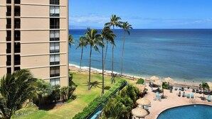 A hotel with a pool, palm trees, and a view of the ocean. - Sweet Studio with AC (Lahaina)