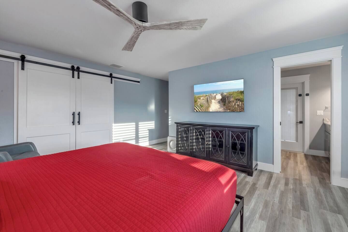 A bedroom with a bed, a wardrobe, a cabinet, a ceiling fan, and a wall-mounted TV.