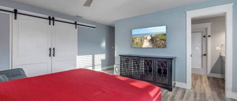 A bedroom with a bed, a wardrobe, a cabinet, a ceiling fan, and a wall-mounted TV.