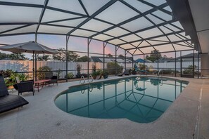 Ein überdachter Innenpool mit Glasdach, umgeben von Liegestühlen und einer überdachten Terrasse.