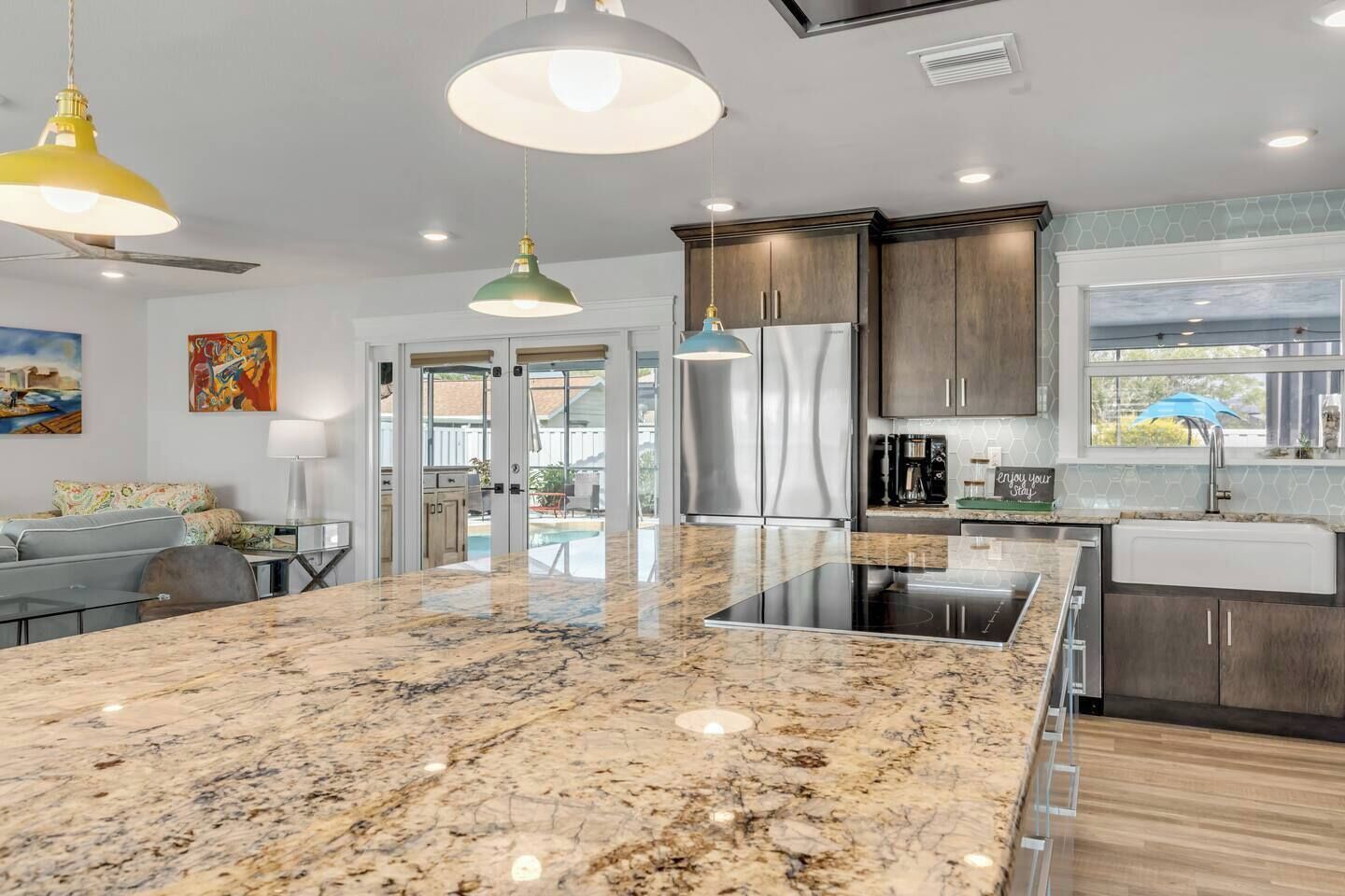 A modern kitchen with a large island, stainless steel appliances, and pendant lighting.