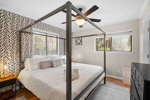 Ein Schlafzimmer mit einem Himmelbett, einem Deckenventilator und einem Fenster mit Jalousien.