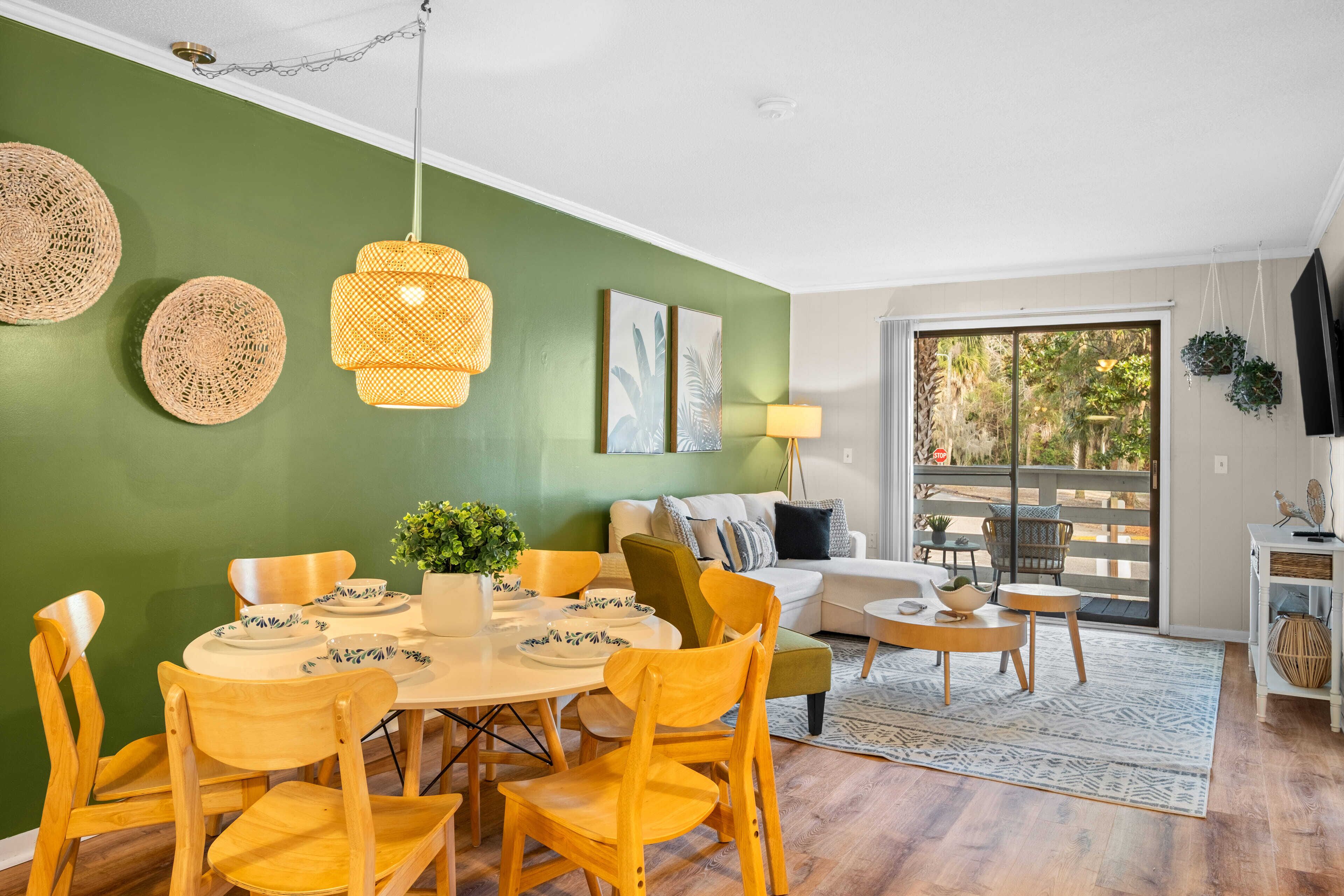 A dining area with a round table, yellow chairs, and a green wall.