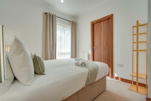 Un dormitorio con cama, una puerta de madera, una ventana con cortinas y una escalera de madera.