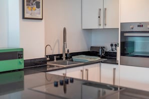 Una cocina moderna con un lavamanos de acero inoxidable, un horno empotrado y un tostador.