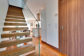 Un interior moderno con una escalera de madera, una zona de cocina y una puerta de madera.