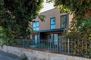 Un bâtiment moderne à deux étages, doté d’une façade en briques, de grandes fenêtres et d’une clôture en métal.