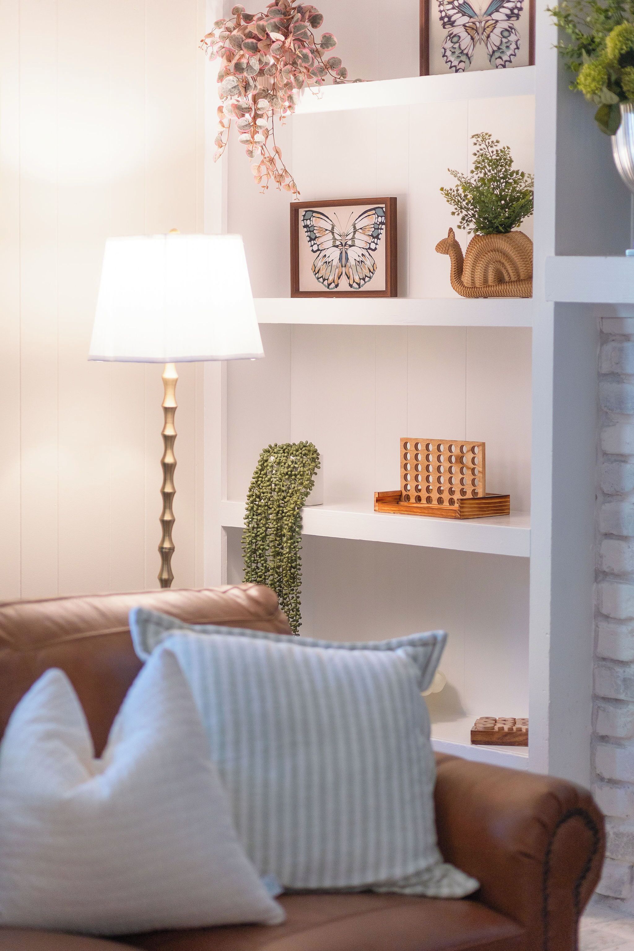 A living room with a brown sofa, a white lamp, and a white fireplace.